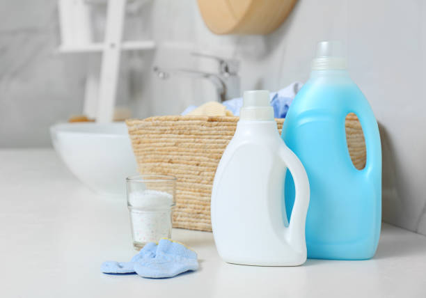 Bottles of detergent and children’s clothes on countertop in bathroom