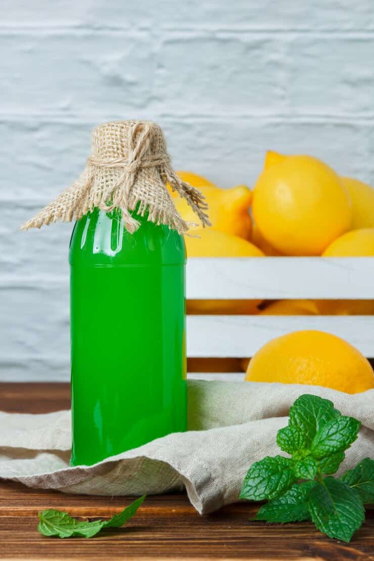 side view lemon juice with lemons wooden crate leaves wooden white surface vertical space text 176474 14145 1