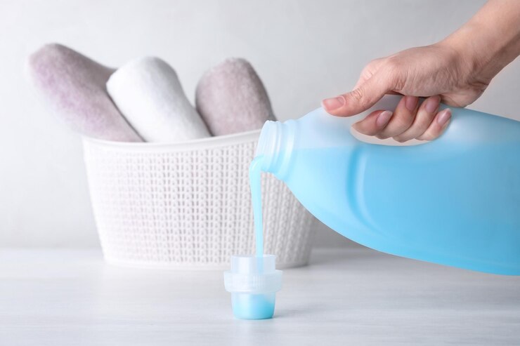 woman pouring laundry detergent into cap table against light background closeup 495423 57769